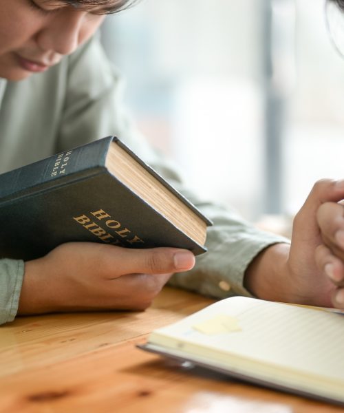 Close-up shot of The Bible and people praying. Close-up shot of The Bible and people praying.